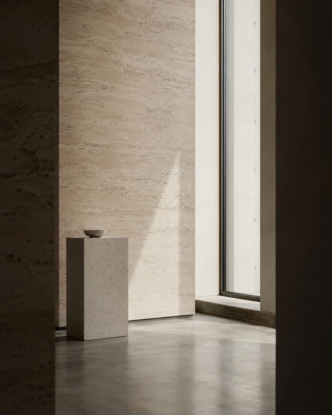 A small ceramic bowl on a travertine plinth against a travertine wall