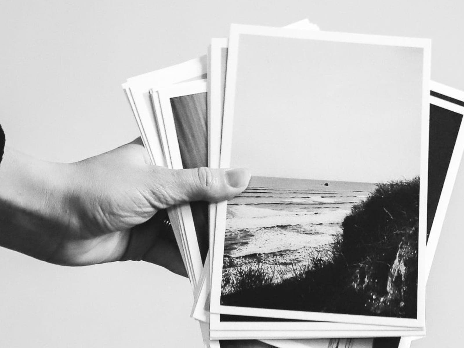 A hand holding a fanned stack of black-and-white photographs